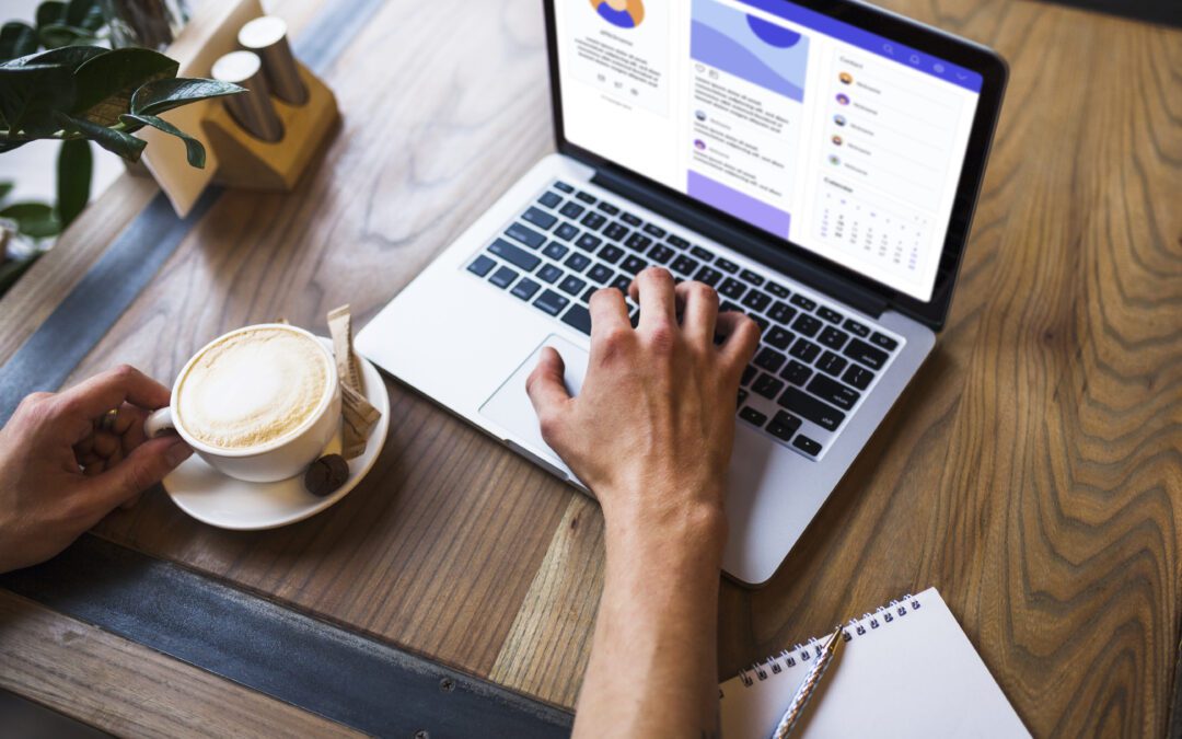 man typing on a laptop while having a sip of coffee